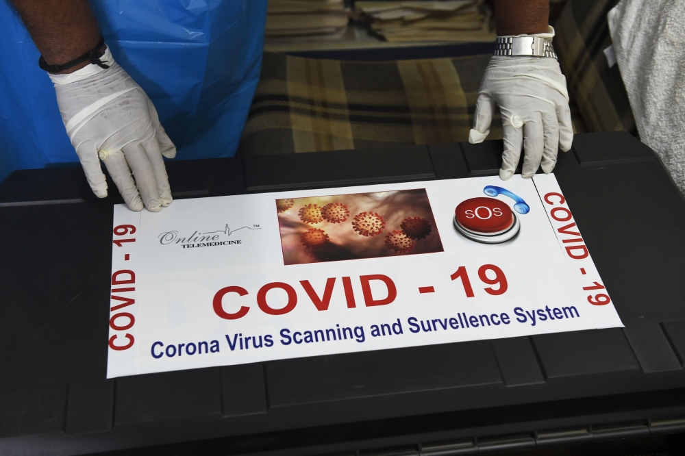 Team member of Ragesh Shah, a scientist and founder of Online Telemedicine Research Institute, puts a sticker on a kit prepared for the coronavirus scanning and surveillance system, in Ahmedabad on March 6, 2020. AFP / SAM PANTHAKY 