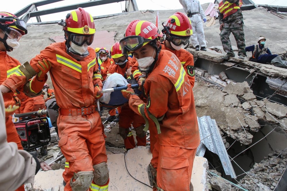 A man (C) is rescued from the rubble of a collapsed hotel in Quanzhou, in China's eastern Fujian province on March 8, 2020. At least four people were killed following the collapse of a hotel used as a coronavirus quarantine facility in eastern China, the 