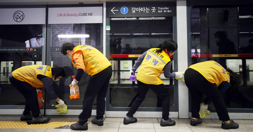 Workers disinfect a screen door to help prevent the spread of the COVID-19 coronavirus, at a subway station in Seoul on March 11, 2020./ AFP / YONHAP / 