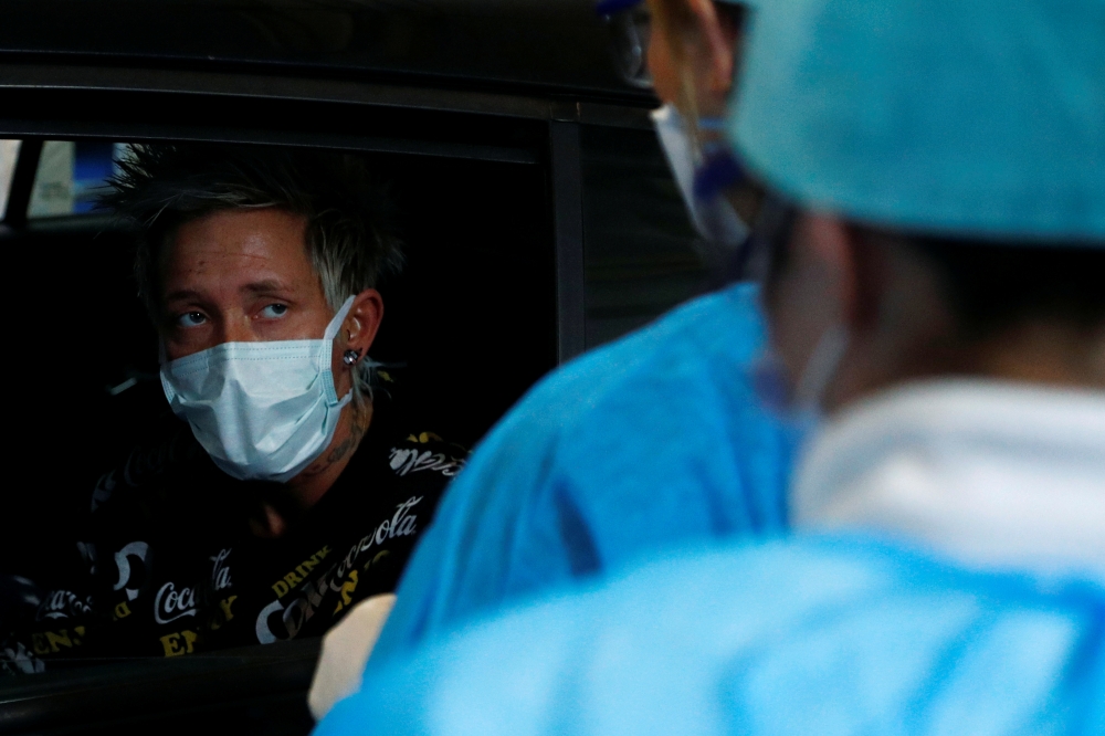 Medical staff check a patient while he sits in his car at a drive-in testing site for coronavirus (COVID-19) at the Regional Hospital Center in Liege, Belgium March 11, 2020. REUTERS/Francois Lenoir