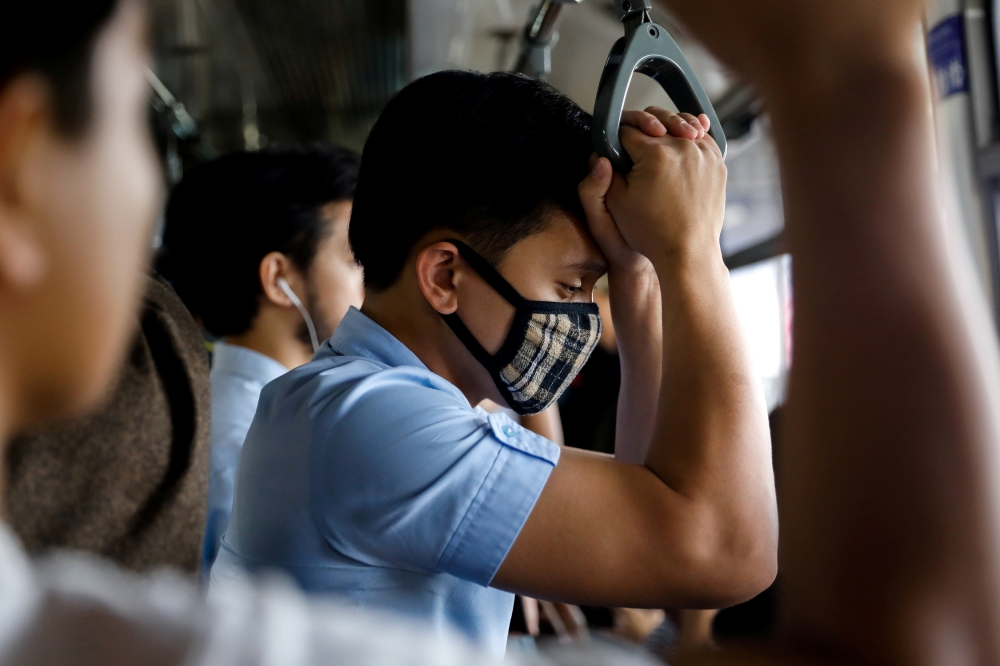 A man wearing a protective mask holds on to a hand rail in a train in Manila, Philippines, March 10, 2020. REUTERS/Eloisa Lopez