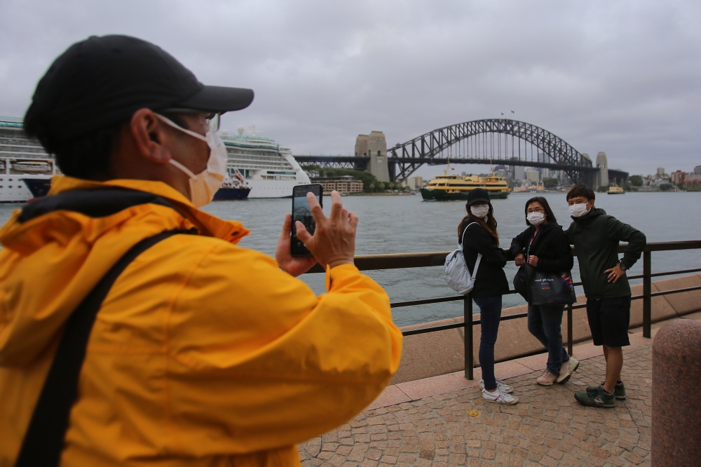 SYDNEY, AUSTRALIA - MARCH 14: People wear face masks as a preventative measure against Coronavirus COVID-19 in front of the Sydney Harbour Bridge in Sydney, Australia on March 14, 2020.  ( Steven Saphore - Anadolu Agency )
