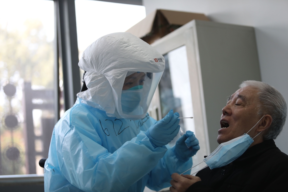 A medical worker takes a swab from a previously recovered COVID-19 coronavirus patient during testing at a hospital in Wuhan, in China's central Hubei province on March 14, 2020. China / AFP / STR