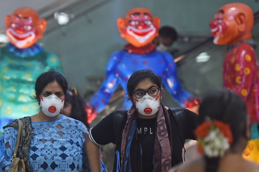  Passengers wearing facemasks amid concerns over the spread of the COVID-19 novel coronavirus, walk inside the airport in Goa on March 15, 2020. (AFP / Punit PARANJPE)
