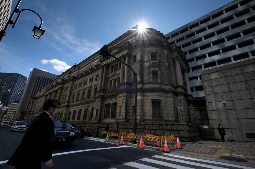 A pedestrian walks in front of the Bank of Japan headquarters in Tokyo on March 16, 2020. The Bank of Japan on March 16 unveiled a series of emergency monetary policy measures to shore up the world's third-largest economy, as the coronavirus pandemic thre