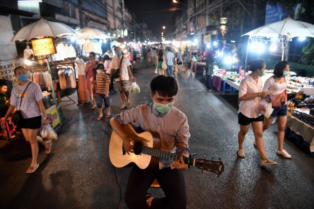  This photo taken on March 14, 2020 shows a man busking in a face mask at an unusually-empty night market in Chiang Mai, as the number of visitors to the region has plunged due to the outbreak of the COVID-19 coronavirus. / AFP / Lillian SUWANRUMPHA