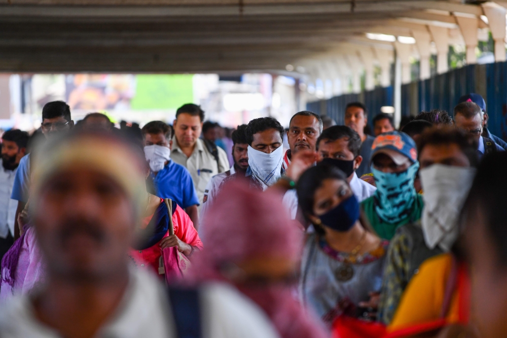 Commuters, some wearing facemasks amid concerns over the spread of the COVID-19 novel coronavirus, make their way along a road in Mumbai on March 13, 2020. / AFP / Indranil MUKHERJEE
