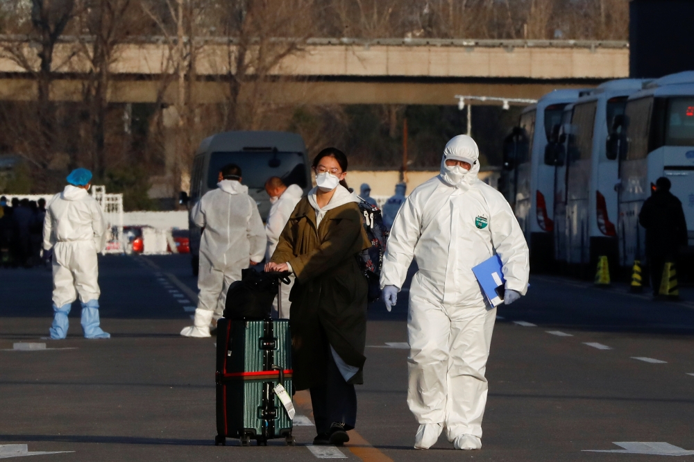 Staff in protective suits accompany passengers outside a centralized facility for screening and registration near the Beijing Capital International Airport in Beijing as the country is hit by an outbreak of the novel coronavirus, China, March 17, 2020. RE