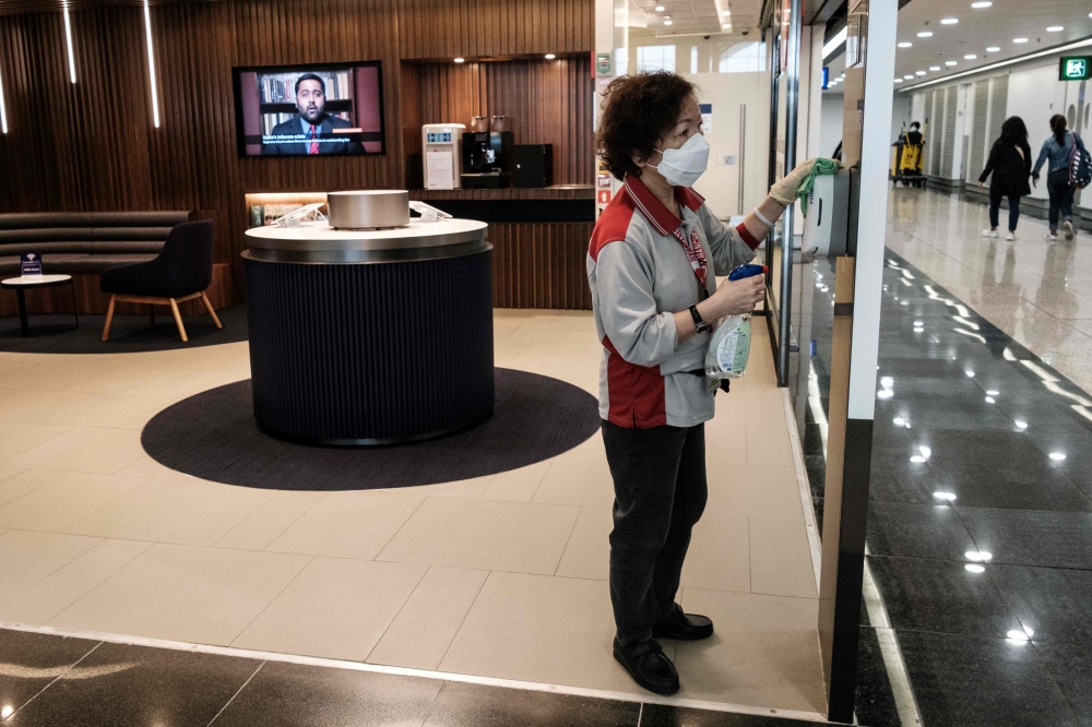 A cleaner wears a face mask as a precautionary measure against the COVID-19 coronavirus as she wipes a surface at Hong Kong’s international airport on March 19, 2020. AFP / Anthony Wallace 