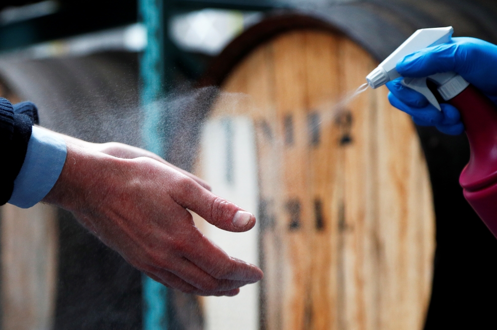 A person disinfects hands at a Belgian distillery that switches its production from gin to disinfecting alcohol during the coronavirus lockdown, imposed by the Belgian government in an attempt to slow down the spread of COVID-19, in Wichelen, Belgium, Mar