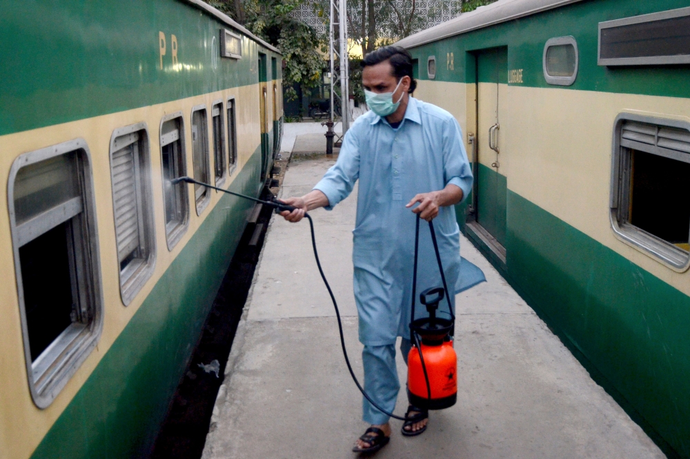 A worker disinfects a passenger train amid concerns over the spread of the COVID-19 novel coronavirus, at Karachi Cantonment railway station in Karachi on March 20, 2020. / AFP 
