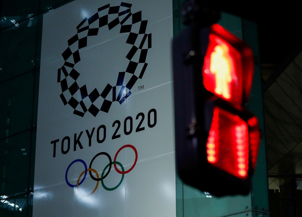 FILE PHOTO : A banner for the upcoming Tokyo 2020 Olympics is seen through a traffic signal in Tokyo, Japan, March 11, 2020. REUTERS/Issei Kato/File Photo

