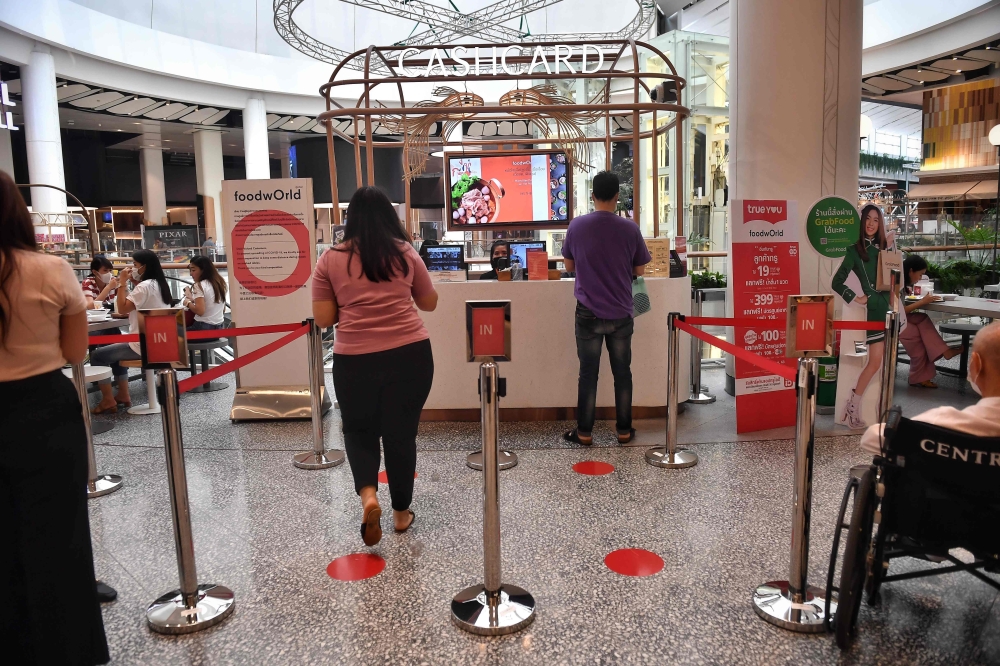 People visit a food court with social distancing markers on the floor at a shopping mall, amid concerns over the spread of the COVID-19 coronavirus, in Bangkok on March 20, 2020. / AFP / Lillian SUWANRUMPHA
