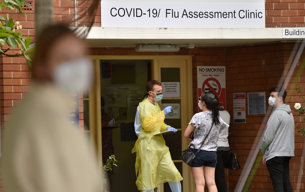 A health worker talks to visitors at a Covid-19 testing centre in Sydney on March 23, 2020. / AFP / PETER PARKS