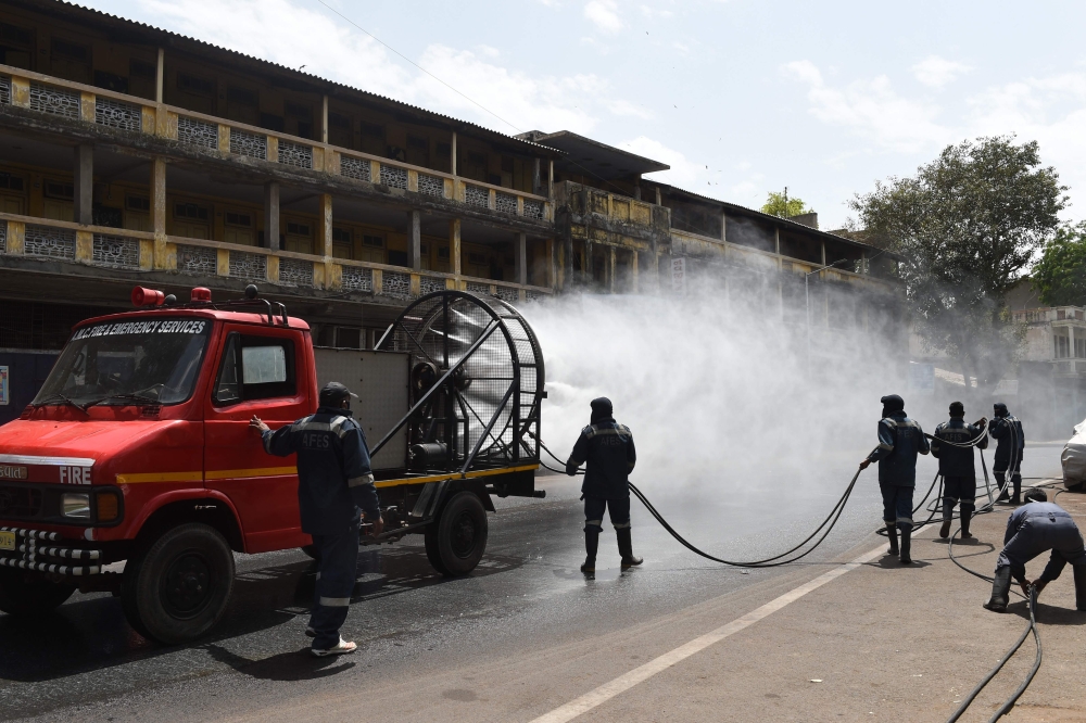 Firefighters from Ahmedabad Fire and Emergency Services spray disinfectant along a street during Gujarat's government-imposed lockdown as a preventive measure against the COVID-19 coronavirus, in Ahmedabad on March 24, 2020. / AFP / SAM PANTHAKY