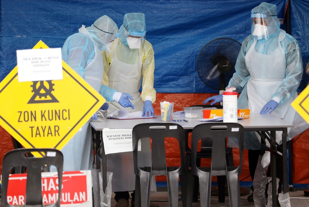 Health workers in protective suits work in a tent erected to test for coronavirus at a clinic, during the movement control order due to the outbreak of the coronavirus disease (COVID-19), in Kuala Lumpur, Malaysia March 23, 2020. REUTERS/Lim Huey Teng
