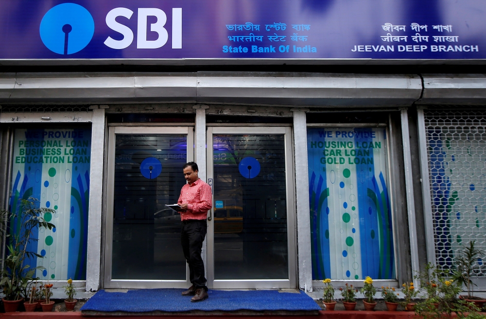 FILE PHOTO: A man checks his mobile phones in front of State Bank of India (SBI) branch in Kolkata, India, February 9, 2018. REUTERS/Rupak De Chowdhuri/File Photo