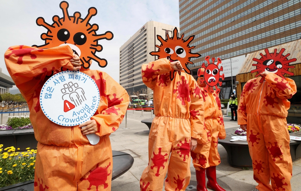 Members of the Asian Citizen's Center for Environment and Health wearing masks depicting the coronavirus perform during a campaign for preventative measures against the COVID-19 coronavirus, in Seoul on March 26, 2020./ AFP / YONHAP / 