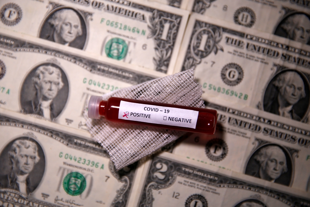 Test tube with fake blood labelled with the coronavirus disease (COVID-19) is placed on dollar banknotes in this illustration taken March 27, 2020. Reuters/Dado Ruvic
