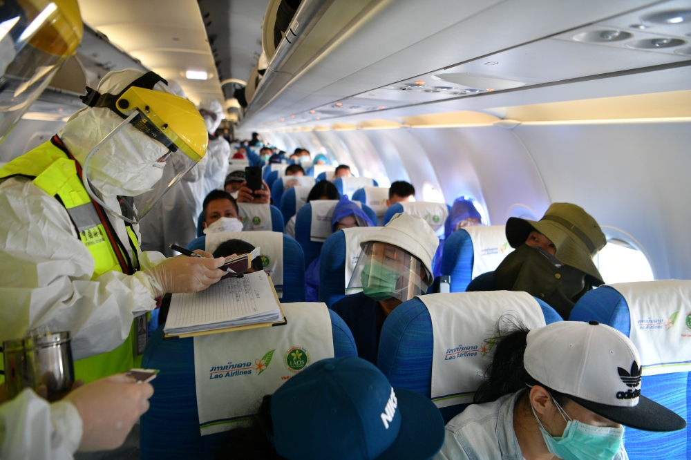 A Chinese customs officer in protective suit inspects documents of passengers on a Lao Airlines flight from Vientiane following a global outbreak of the coronavirus disease (COVID-19), at Kunming Changshui International Airport in Kunming, Yunnan province