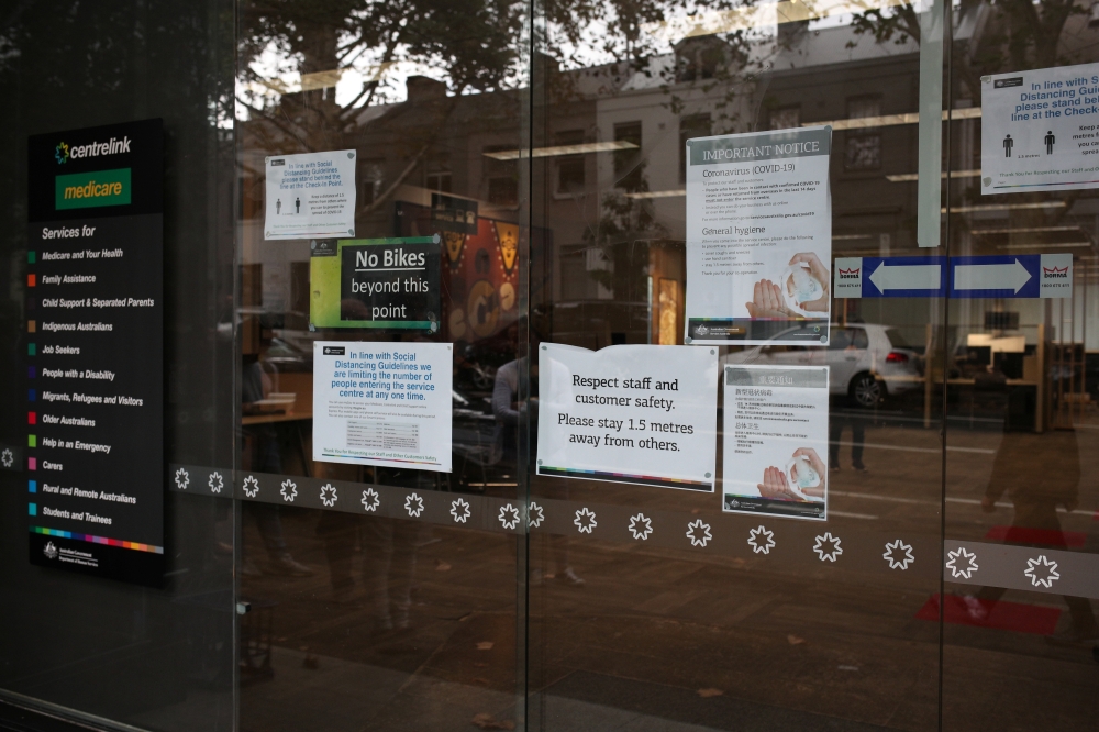 Signs on social distancing and the coronavirus disease (COVID-19) are seen outside a Centrelink office in Sydney, in the wake of New South Wales implementing measures shutting down non-essential businesses and moving toward harsh penalties to enforce self