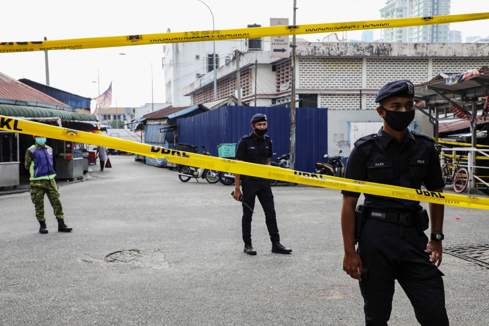 Police officers stand guard at an entrance of a market, during the movement control order due to the outbreak of the coronavirus disease (COVID-19), in Kuala Lumpur, Malaysia March 27, 2020. REUTERS/Lim Huey Teng