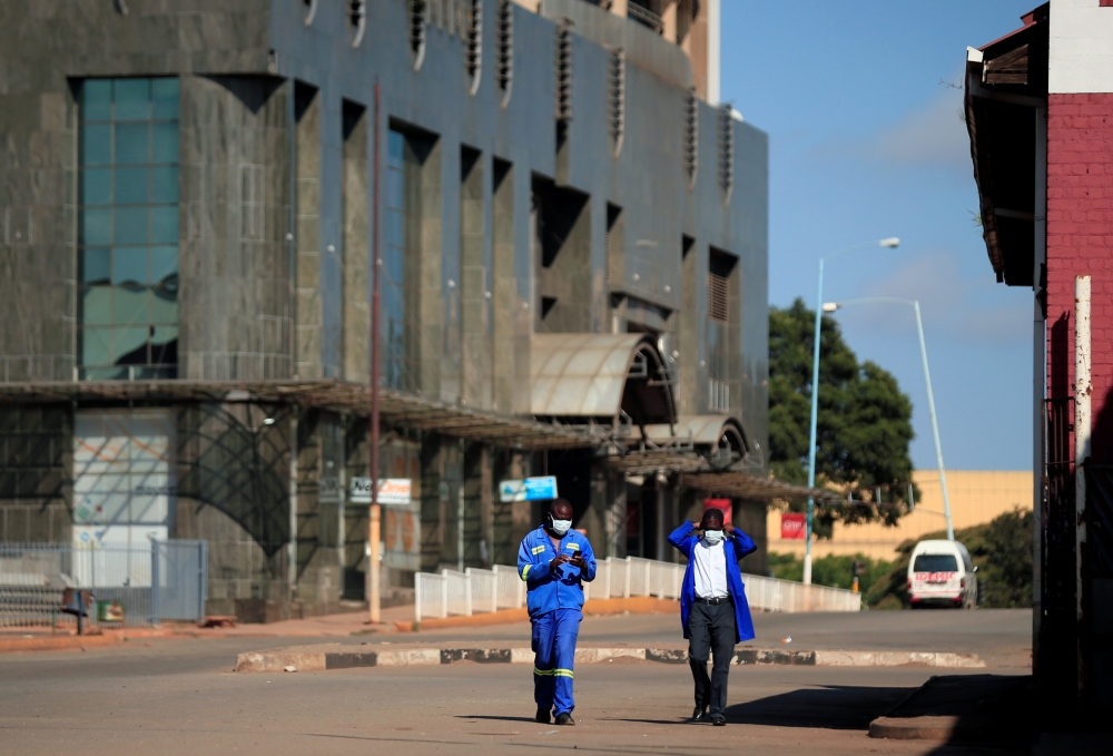 Men wear protective masks as they walk down a deserted street on the first day of the 21-day nationwide lockdown aimed at limiting the spread of coronavirus disease (COVID-19) in Harare, Zimbabwe, March 30, 2020. REUTERS/Philimon Bulawayo