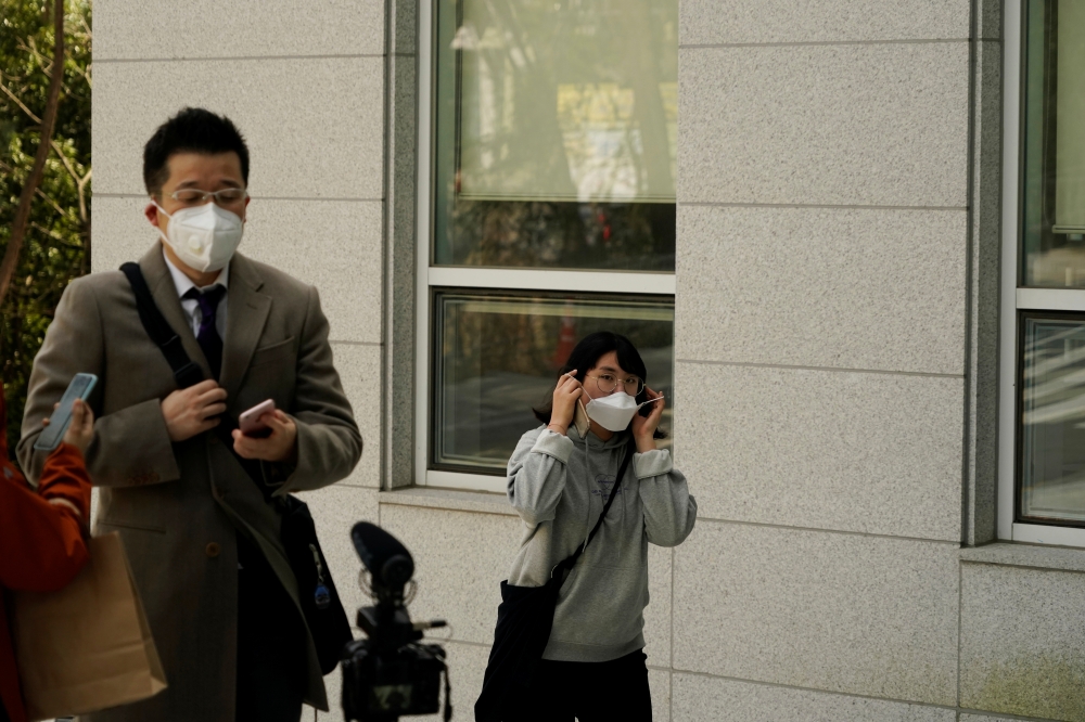 A student wearing a mask to prevent contracting the coronavirus walks past a professor of Pusan National University Park Hyun who used to be a coronavirus patient as he have an interview with Reuters at Pusan National University in Busan, South Korea, Mar