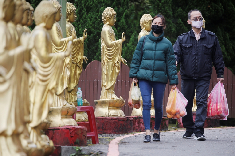 Family members wearing face masks, for protection against the coronavirus disease (COVID-19), carry fruits to pay their respects to their loved ones for tomb-sweeping festival at a columbarium in Taipei, Taiwan, March 29, 2020. REUTERS/Ann Wang