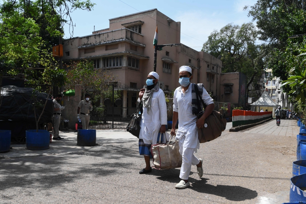 Men wearing a protective facemasks walk to board a special service bus taking them to a quarantine facility amid concerns about the spread of the COVID-19 coronavirus in Nizamuddin area of New Delhi on March 31, 2020. AFP / Sajjad Hussain 