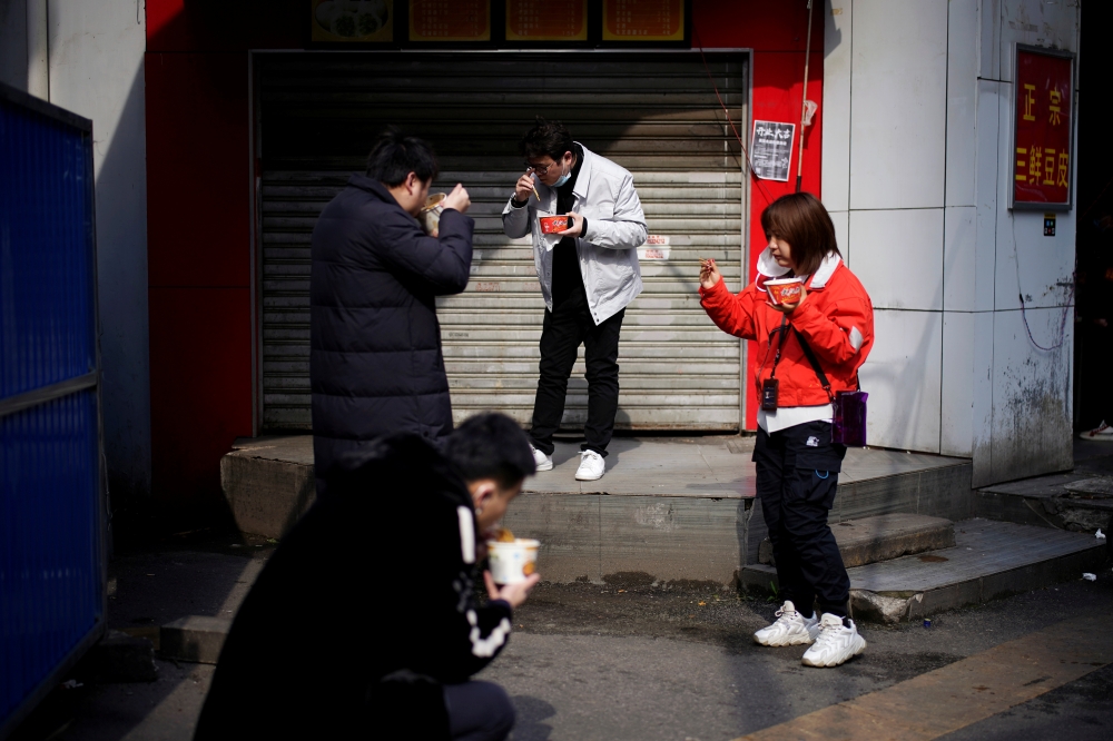 People eat their breakfast near a closed store and a barricade in Wuhan, Hubei province, the epicentre of China's coronavirus disease (COVID-19) outbreak, April 1, 2020. REUTERS/Aly Song