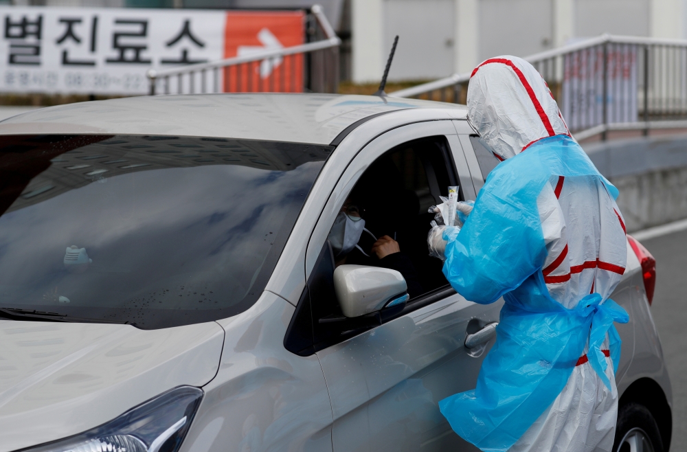 FILE PHOTO: A medical staff member in protective gear prepares to take samples from a visitor at a 'drive-thru' testing center for the novel coronavirus disease of COVID-19 in Yeungnam University Medical Center in Daegu, South Korea, March 3, 2020. REUTER