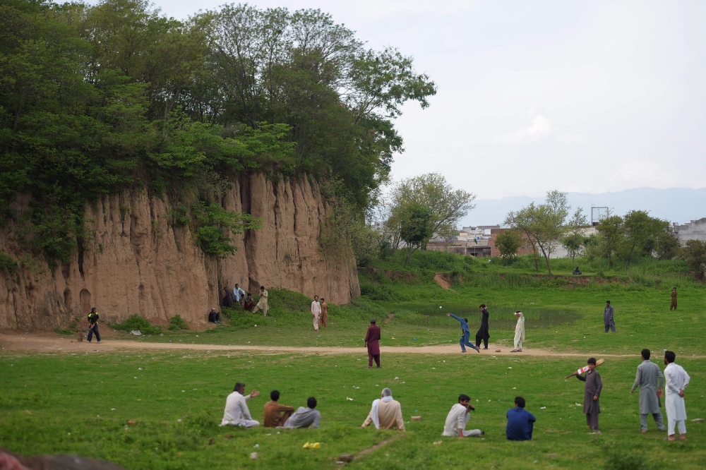 Pakistani youth play cricket on a field during a government-imposed nationwide lockdown against the COVID-19 coronavirus on the outskirts of Islamabad on April 1, 2020.  / AFP / Farooq NAEEM