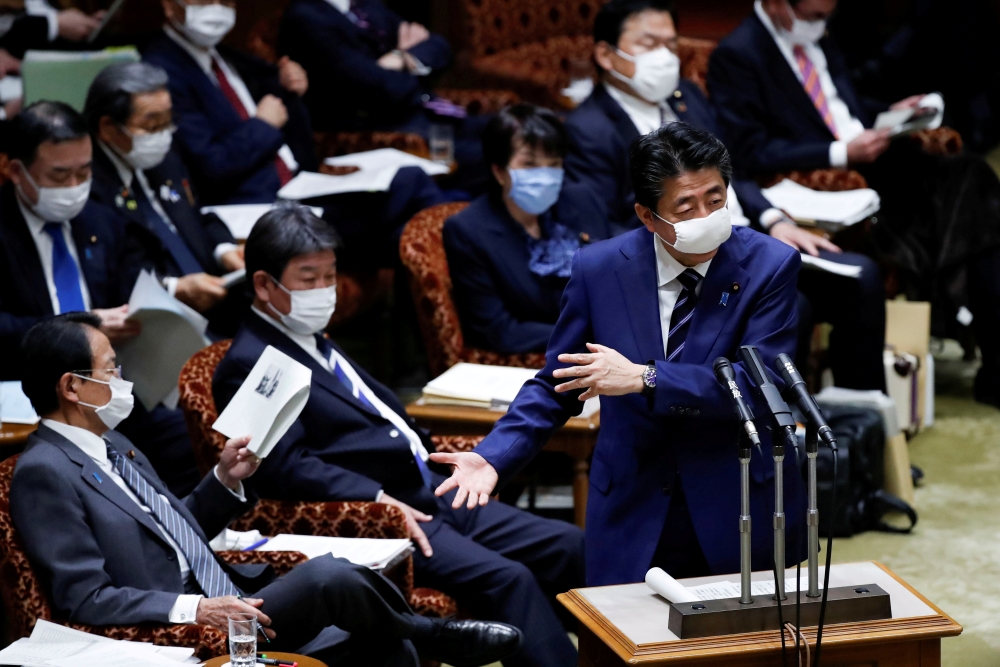 File photo: Japan's Prime Minister Shinzo Abe, wearing a protective face mask, gestures next to Japan's Finance Minister Taro Aso during an upper house parliamentary session, following an outbreak of the coronavirus disease (COVID-19), in Tokyo, Japan Apr