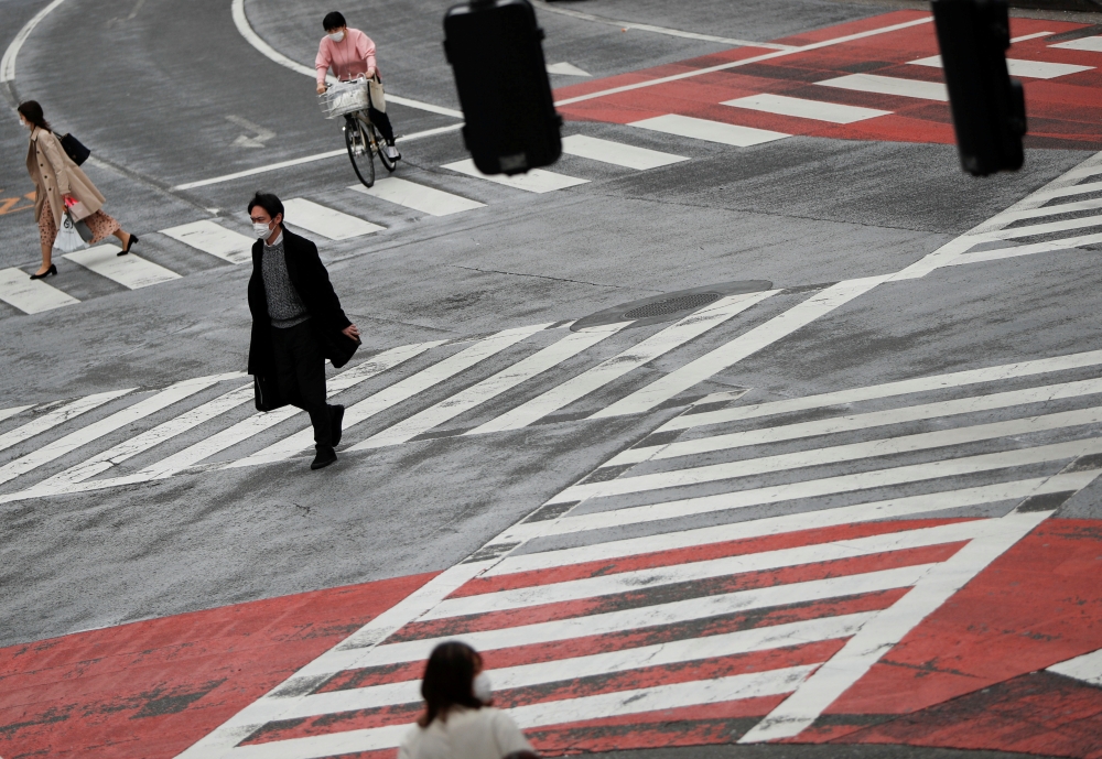 Pedestrians wearing protective face masks, following an outbreak of the coronavirus disease (COVID-19), walk on the crossing at Shibuya shopping and amusement district in Tokyo, Japan March 31, 2020. REUTERS/Issei Kato/File Photo
 