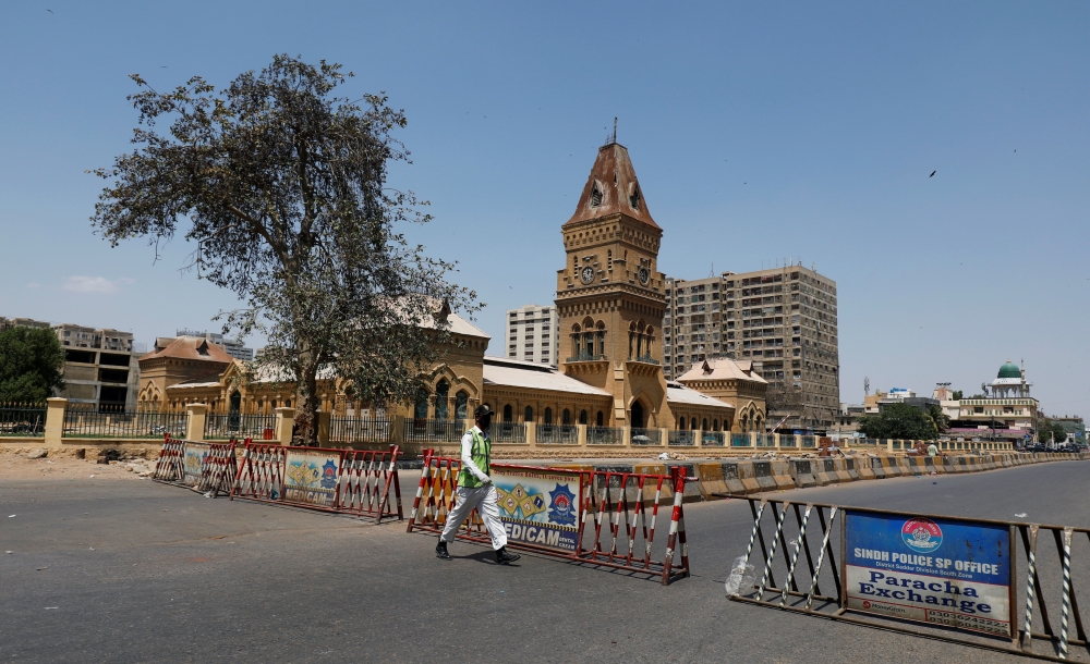 :A traffic police officer walks past barriers used to block the road in front of the British era Empress Market building, during a lockdown after Pakistan shut all markets, public places and discouraged large gatherings amid an outbreak of coronavirus dis