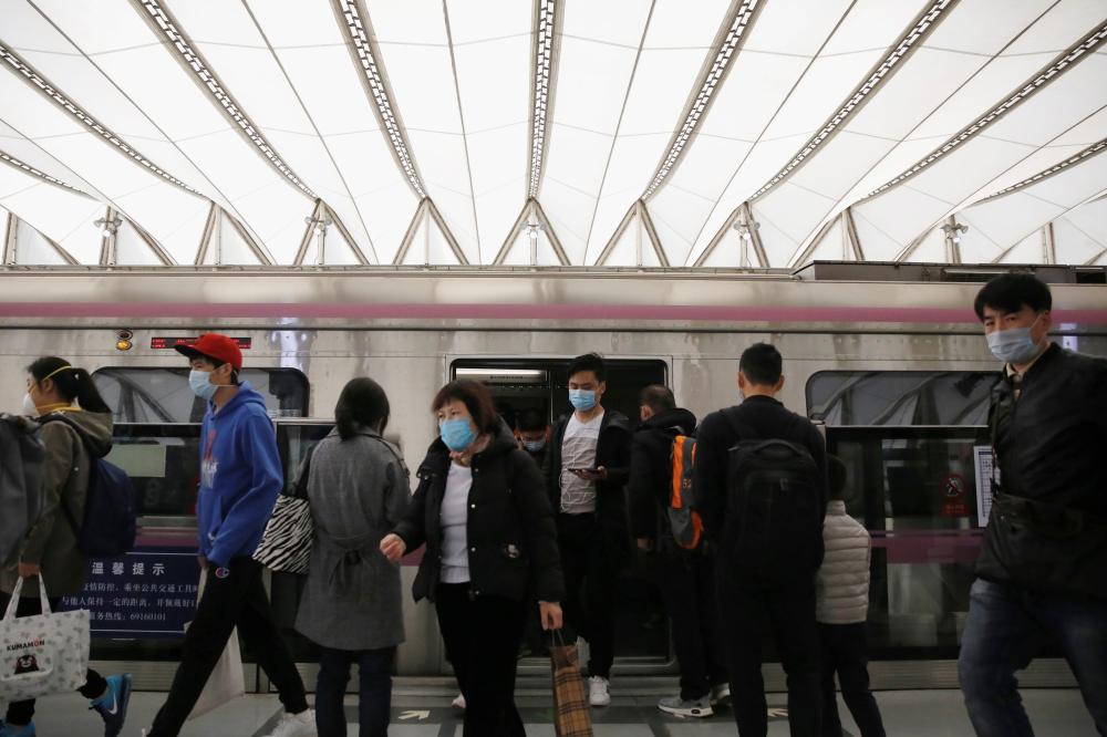 People wearing face masks get off a subway train at a subway station during morning rush hour in Beijing, as the spread of the novel coronavirus disease (COVID-19) continues in the country, in China April 7, 2020. REUTERS/Tingshu Wang