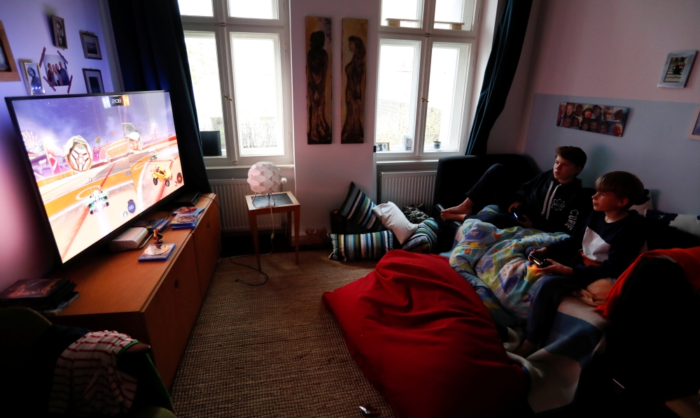 Malte and Rasmus Bruhn play a video game after dinner at home as the spread of the coronavirus disease (COVID-19) continues in Berlin, Germany, April 1, 2020. REUTERS/Fabrizio Bensch
