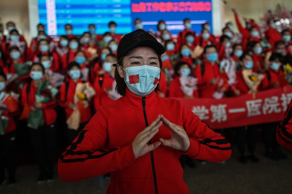 A medical staff member from Jilin Province tears up during a ceremony before leaving as Tianhe Airport is reopened in Wuhan in China's central Hubei province on April 8, 2020. / AFP / Hector RETAMAL