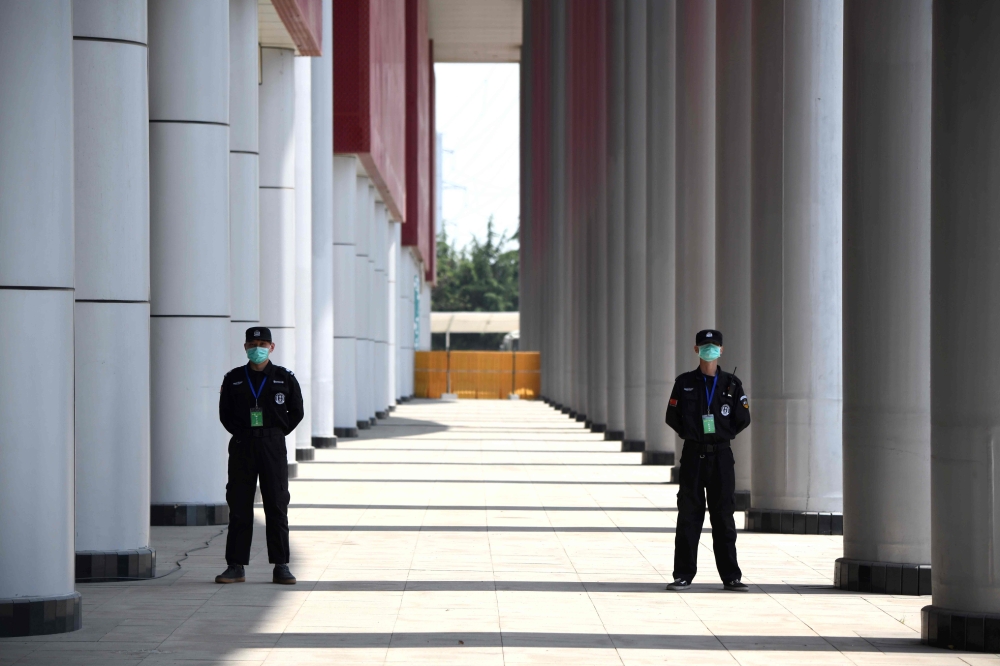 Security personnel stand outside a field hospital that had offered beds for COVID-19 coronavirus patients during the height of the crisis in Wuhan in China’s central Hubei province on April 9, 2020. AFP / Noel Celis