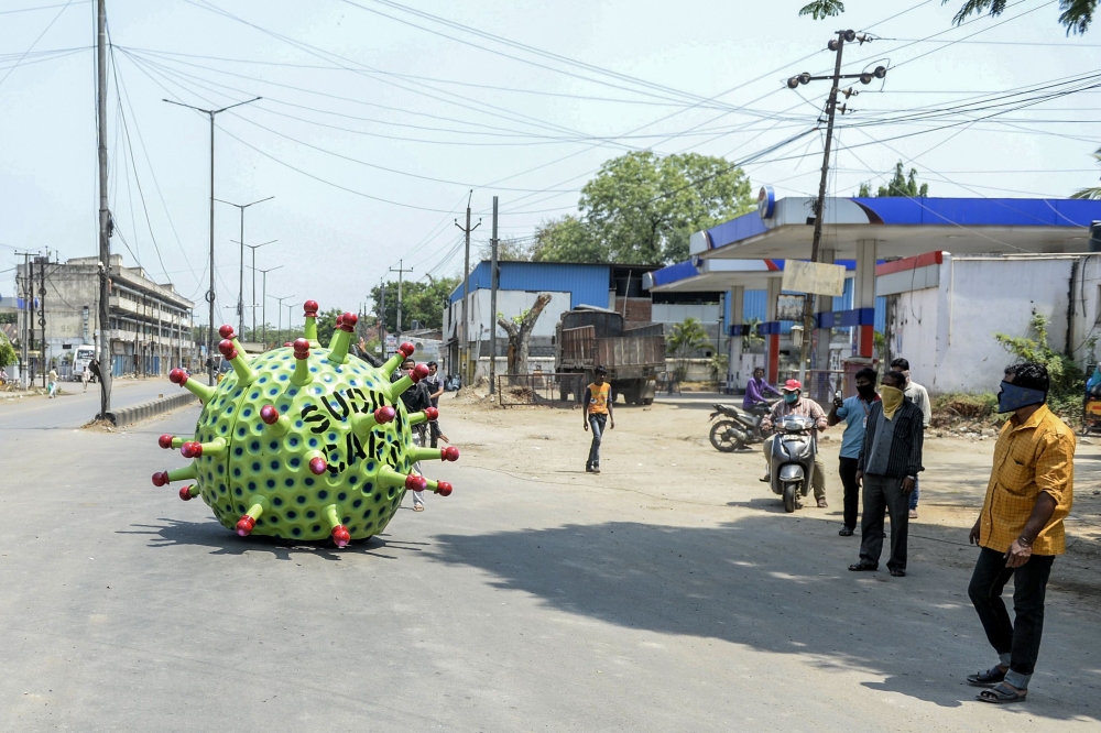 People stop to watch as inventor Sudhakar Yadav (inside) leads his coronavirus-themed made car on a road for an awareness campaign during a government-imposed nationwide lockdown as a preventive measure against the COVID-19 coronavirus, in Hyderabad on Ap