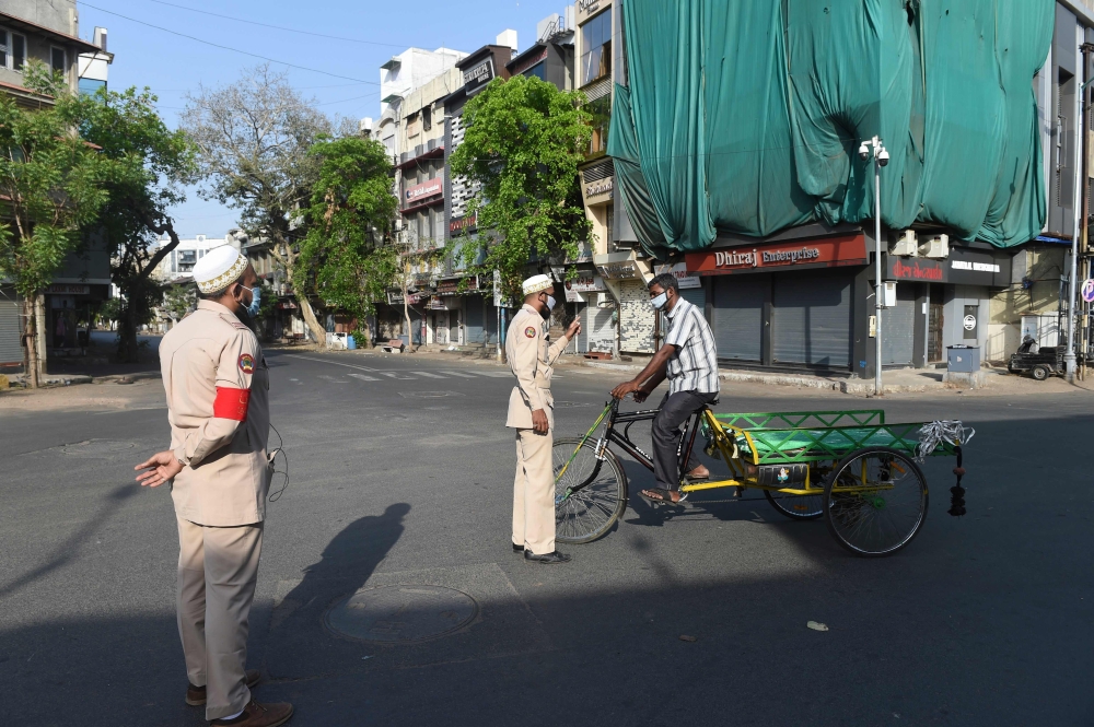 Volunteers affiliated to Burhani Guards International speak with a man on an empty road as they patrol an area during a government-imposed nationwide lockdown as a preventive measure against the COVID-19 coronavirus, in Ahmedabad on April 10, 2020. / AFP 