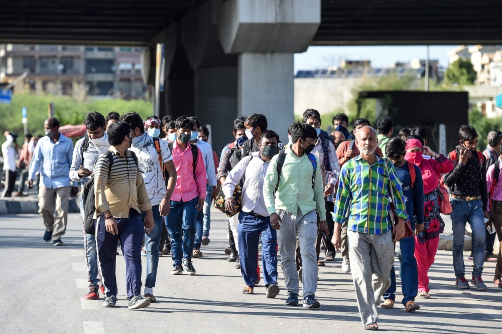 (FILES) In this file photo taken on March 27, 2020 migrant workers and their family members walk carrying their belongings on a highway towards Uttar Pradesh state as they leave to go back to their villages during a government-imposed nationwide lockdown 