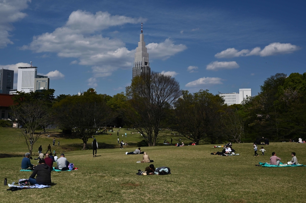 People relax at Meiji park in Tokyo on April 11, 2020. Japan on April 7 declared a month-long state of emergency over a spike in coronavirus cases, ramping up efforts to contain infections but stopping short of the strict lockdowns seen in other parts of 
