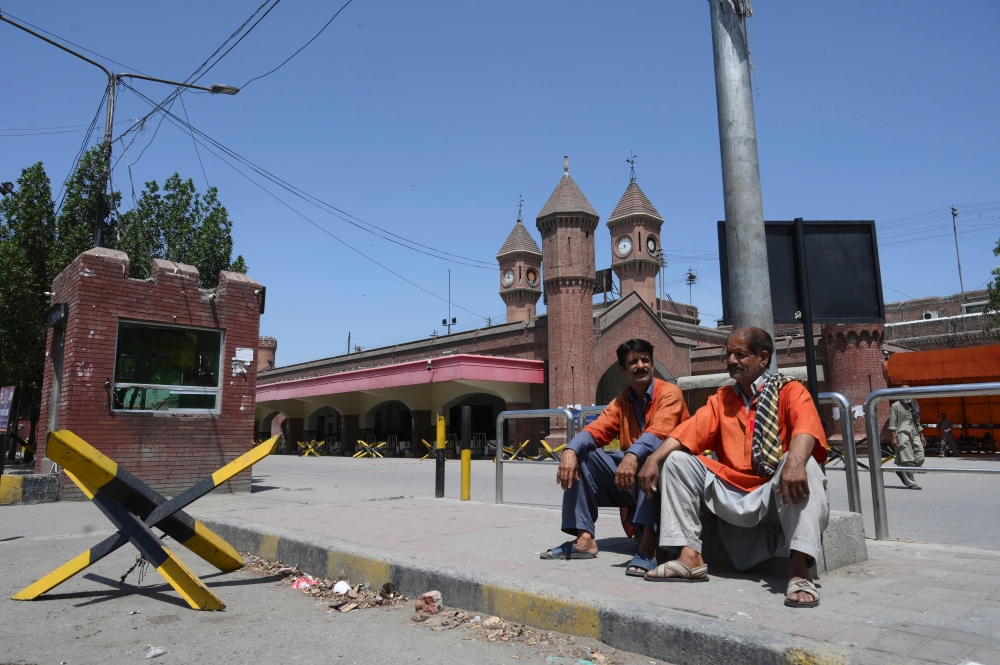 Railway porters sit outside a railway station during a government-imposed nationwide lockdown as a preventive measure against the COVID-19 coronavirus, in Lahore on April 12, 2020. / AFP / ARIF ALI