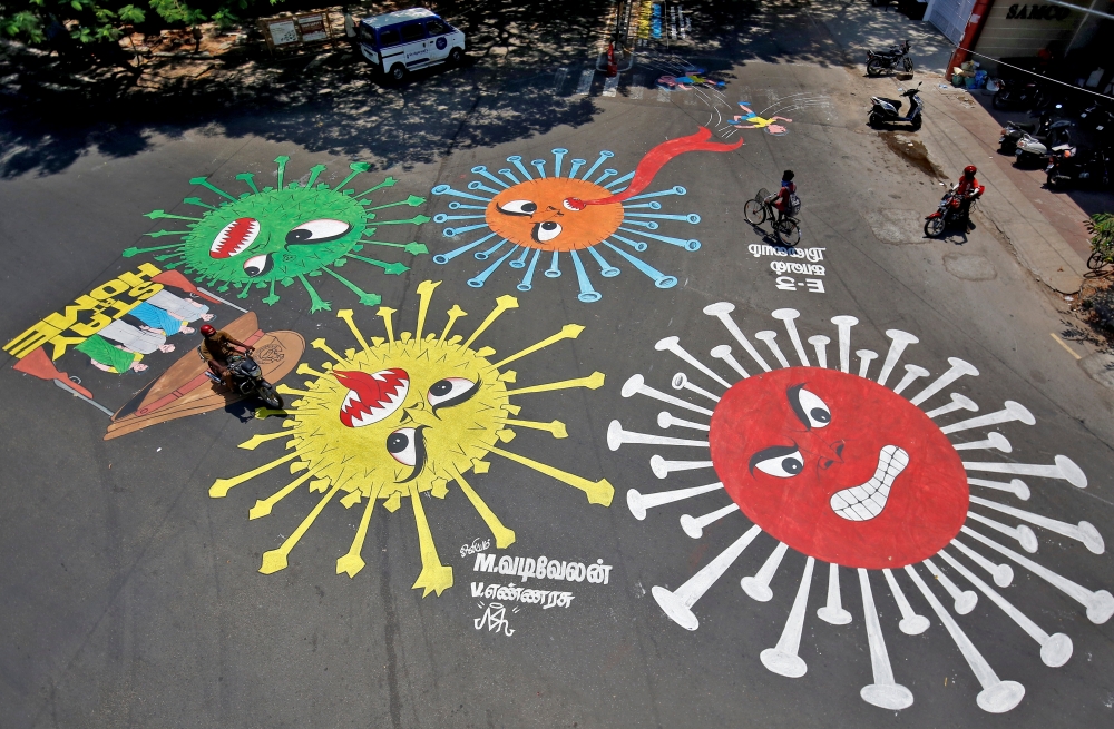 People move past graffiti on a road depicting the coronavirus as an attempt to raise awareness about the importance of staying at home during a 21-day nationwide lockdown to slow the spreading of the coronavirus disease (COVID-19), in Chennai, India, Apri