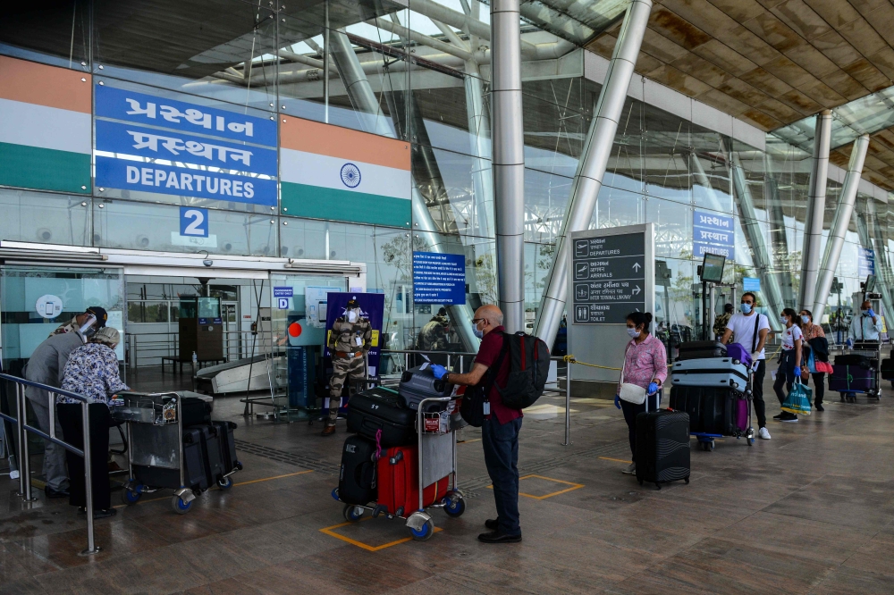 :British nationals queue up outside a departures terminal before boarding a special British Airways flight during Indian government-imposed nationwide lockdown as a preventive measure against the COVID-19 coronavirus, at the Sardar Vallabhbhai Patel Inter