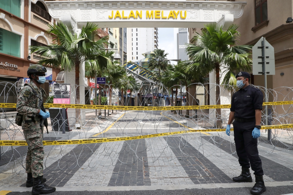 A soldier and a police officer stand guard at an entrance of the red zone under enhanced lockdown, during the movement control order due to the outbreak of the coronavirus disease (COVID-19), in Kuala Lumpur, Malaysia April 15, 2020. REUTERS/Lim Huey Teng