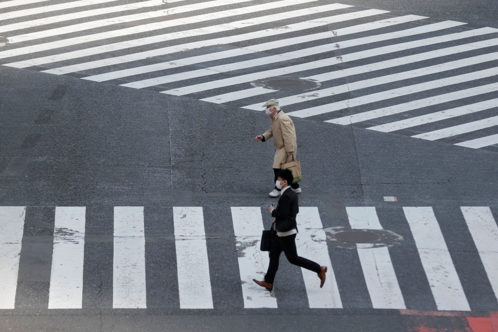 People in face masks cross a near-empty street after the government announced a state of emergency for the capital and some prefectures following the coronavirus disease (COVID-19) outbreak, in Tokyo, Japan April 16, 2020. REUTERS/Kim Kyung-Hoon