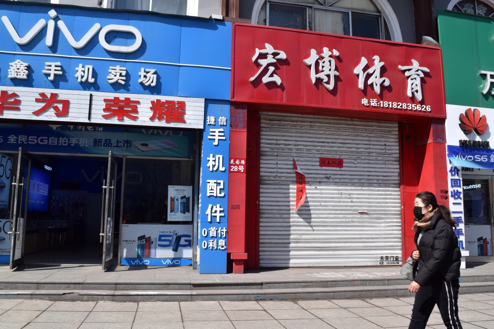 A resident wearing a face mask walks past a closed shop in Suifenhe, a city of Heilongjiang province on the border with Russia, as the spread of the novel coronavirus disease (COVID-19) continues in the country, China April 12, 2020. REUTERS/Huizhong Wu